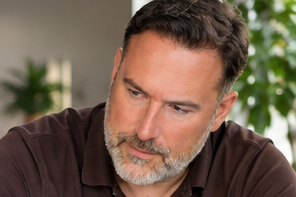Carsten Meyer im braunen Hemd, nachdenklich nach unten blickend.