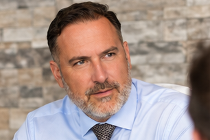 Carsten Meyer im hellblauen Hemd, im Gespräch mit einer Person vor einer hellen Steinwand.